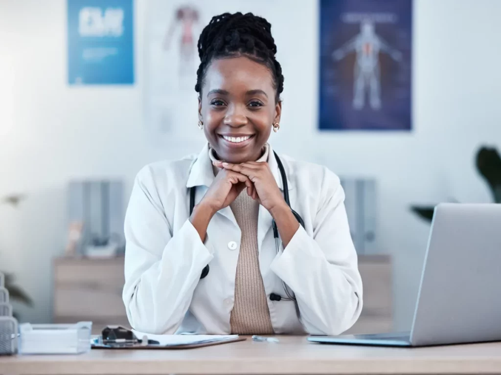 A primary Care Doctor smiling with hands on her chin