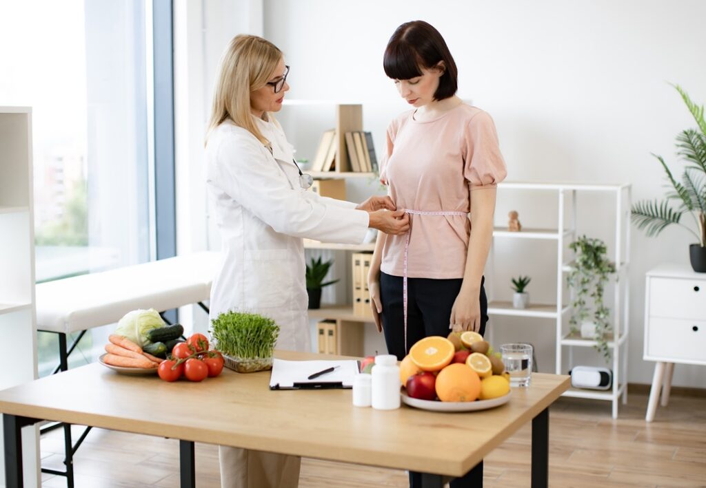 A doctor using tape rule to check the waist of a patient