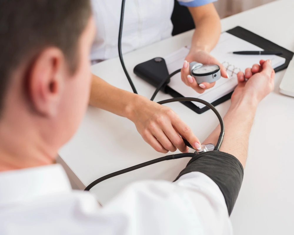 Healthcare provider measuring a patient’s blood pressure with a manual cuff and stethoscope during a routine medical exam.