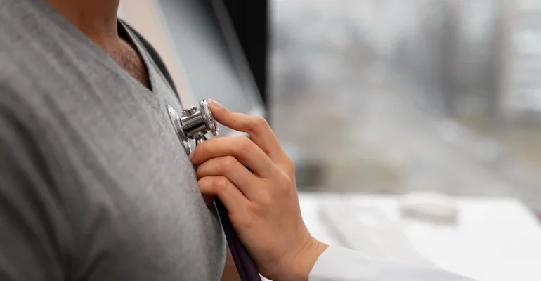 A healthcare professional using a stethoscope to listen to a patient’s chest during a medical examination.