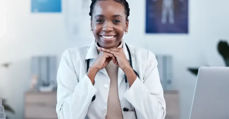 A primary Care Doctor smiling with hands on her chin